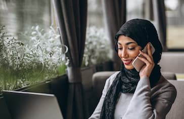 Arabian woman in hijab inside a cafe working on laptop