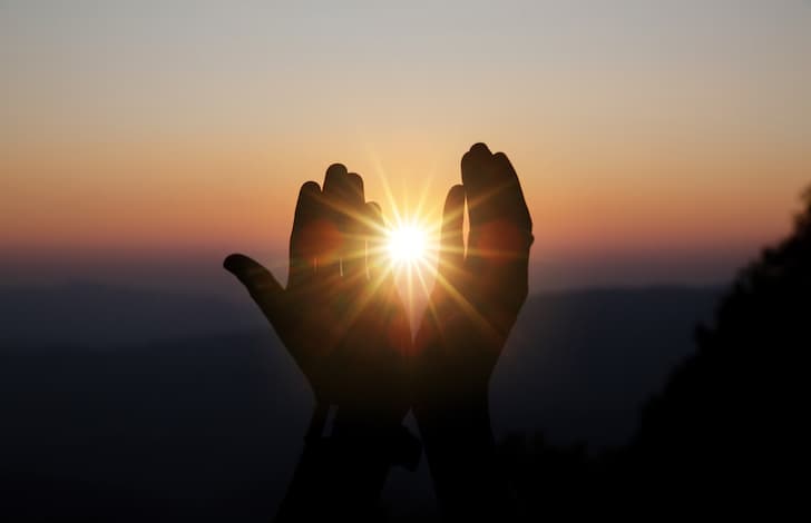 Faith of christian concept: Spiritual prayer hands over sun shine with blurred beautiful sunset background