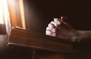 hands-praying-holy-bible-beside-window-light_featureimagejpg